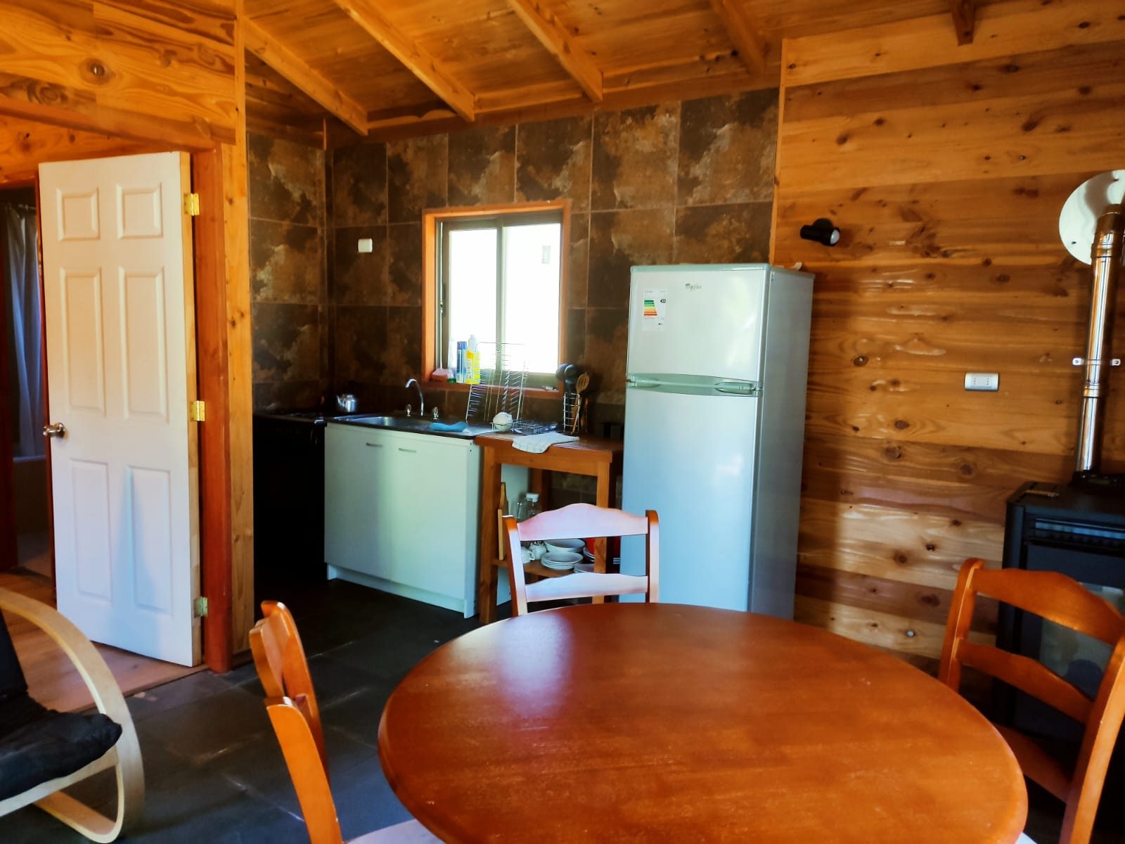 Cocina equipada de cabaña con refrigerador y mesa de comedor